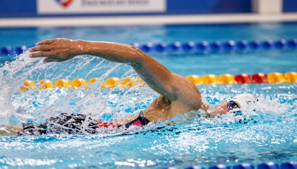 A dynamic underwater scene showcasing the powerful and streamlined legs of a swimmer performing the crawl stroke. The foreground captures a swimmer in modest athletic attire, expertly propelling themselves through the water with a rhythmic flutter kick. The focus is on the legs, elegantly positioned to illustrate the balance between propulsion and stabilization. In the middle ground, the shimmering water reflects light, enhancing the fluid motion, while bubbles trail behind the swimmer, indicating speed. The background features a blurred pool setting, hinting at competition. The lighting is bright and clear, accentuating the swimmer's form against the blue hues of the water, creating an energetic and motivational atmosphere that embodies strength and technique.